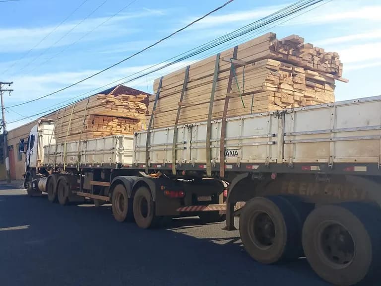 Carreta com madeira serrada estacionada na rua para entrega